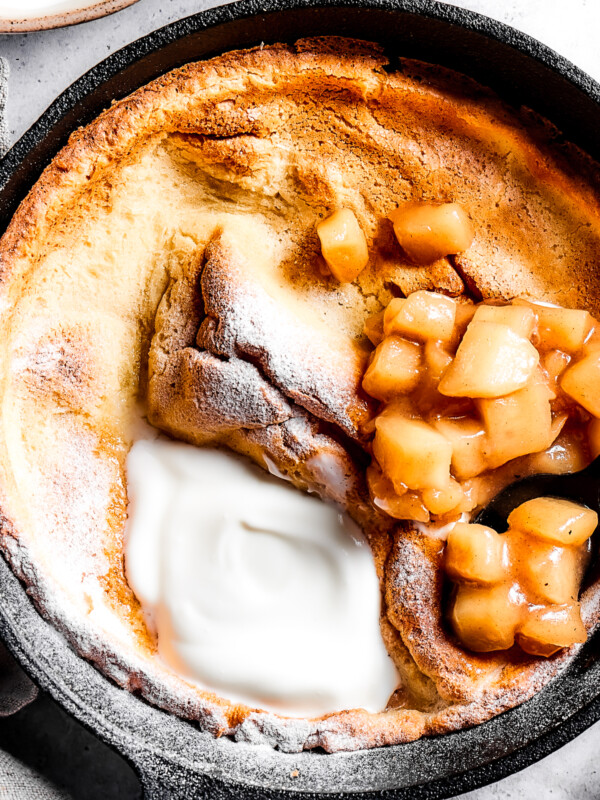 A skillet pancake with apples and creamy topping.