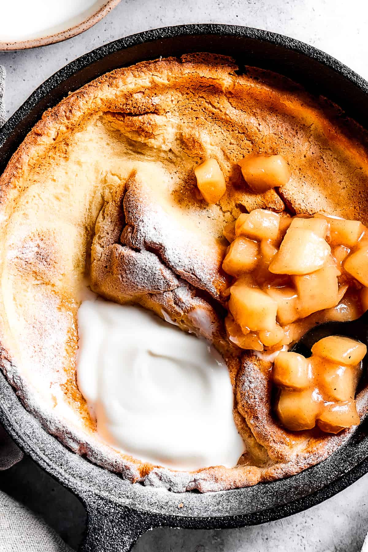 A skillet pancake with apples and creamy topping.