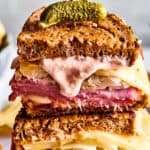Two Reuben sandwich halves with Russian dressing dripping from one.