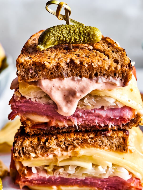 Two Reuben sandwich halves with Russian dressing dripping from one.