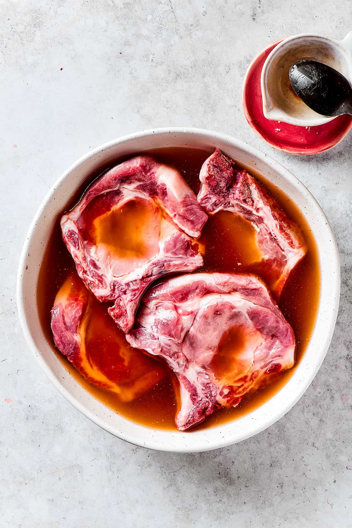 Pork Chops Soaking in Flavorful Brine Pork chops fully submerged in a balsamic vinegar and salt brine, covered and ready for refrigeration.
