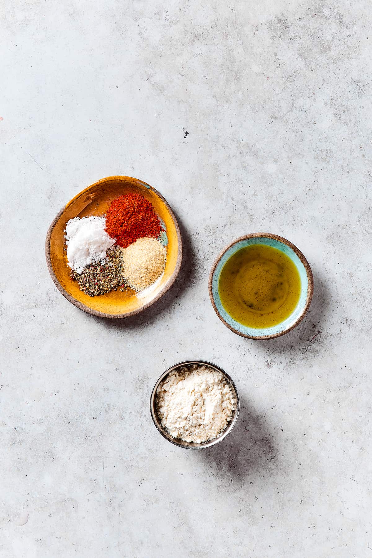 Mixing Seasonings for Pork Chop Coating A bowl of seasonings including flour, salt, pepper, garlic powder, and smoked paprika, alongside olive oil.