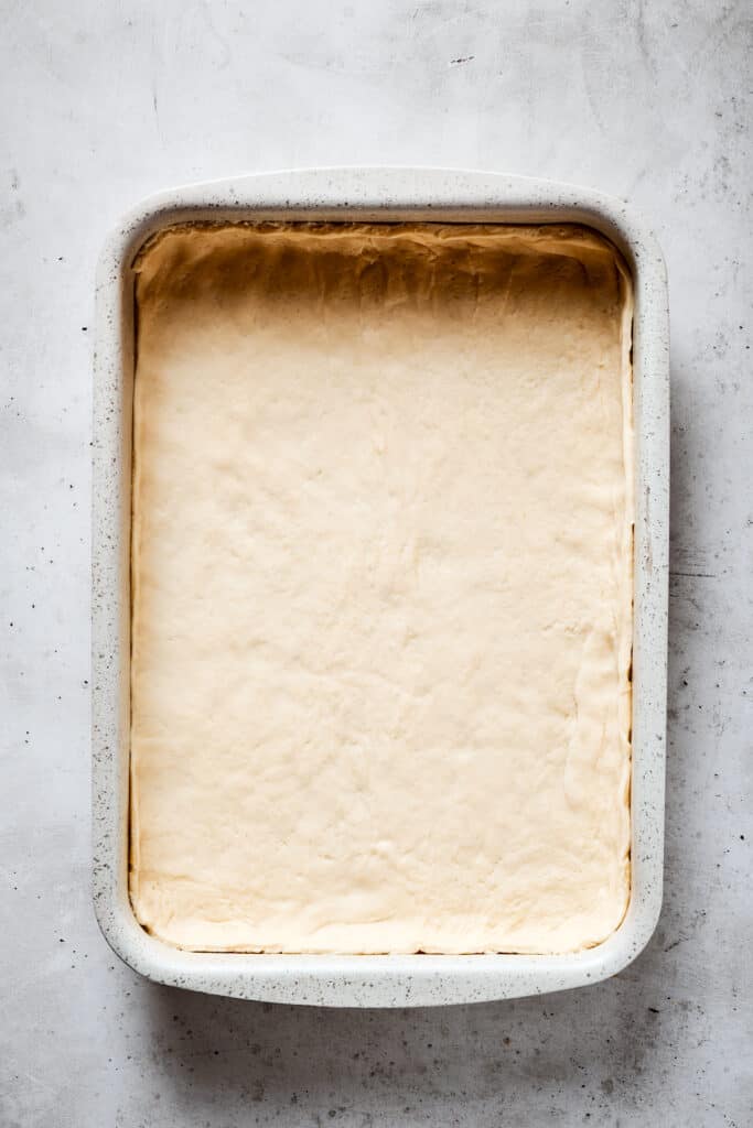 A baking dish lined with crescent roll dough.