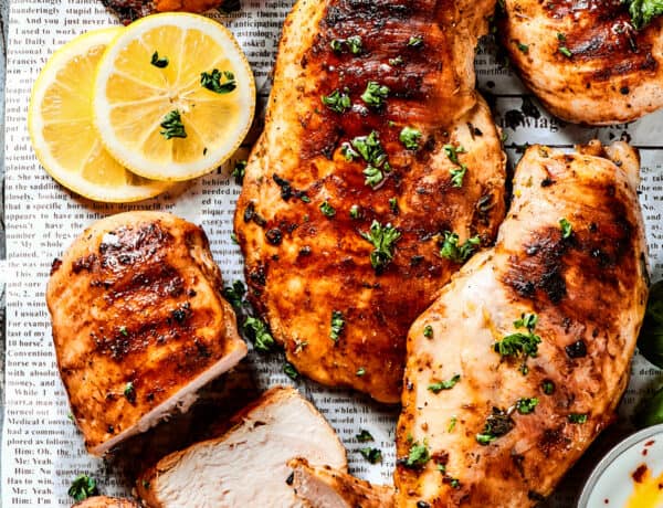 A sheet pan of lemon chicken with fresh herbs and lemon slices.
