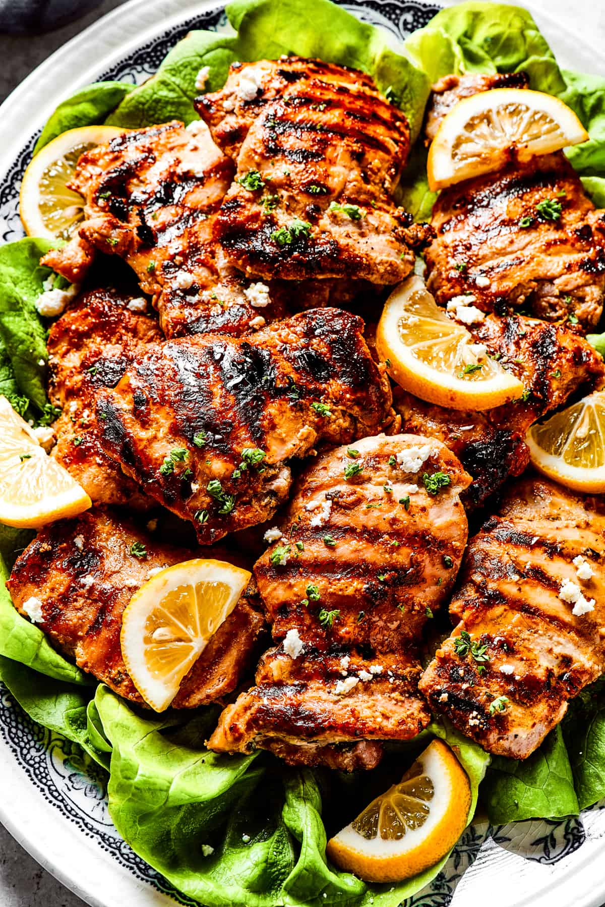 Yogurt-marinated chicken grilled set atop a bed of lettuce leaves and topped with feta cheese.
