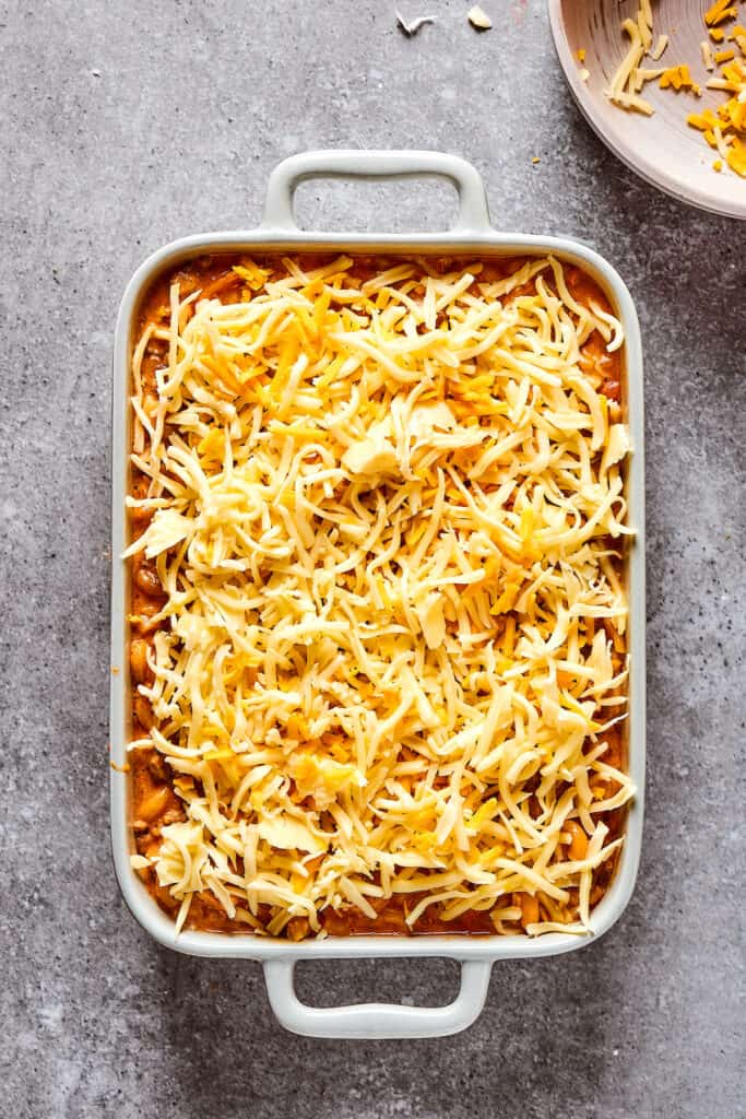 Overhead shot of a casserole dish covered in shredded cheese.