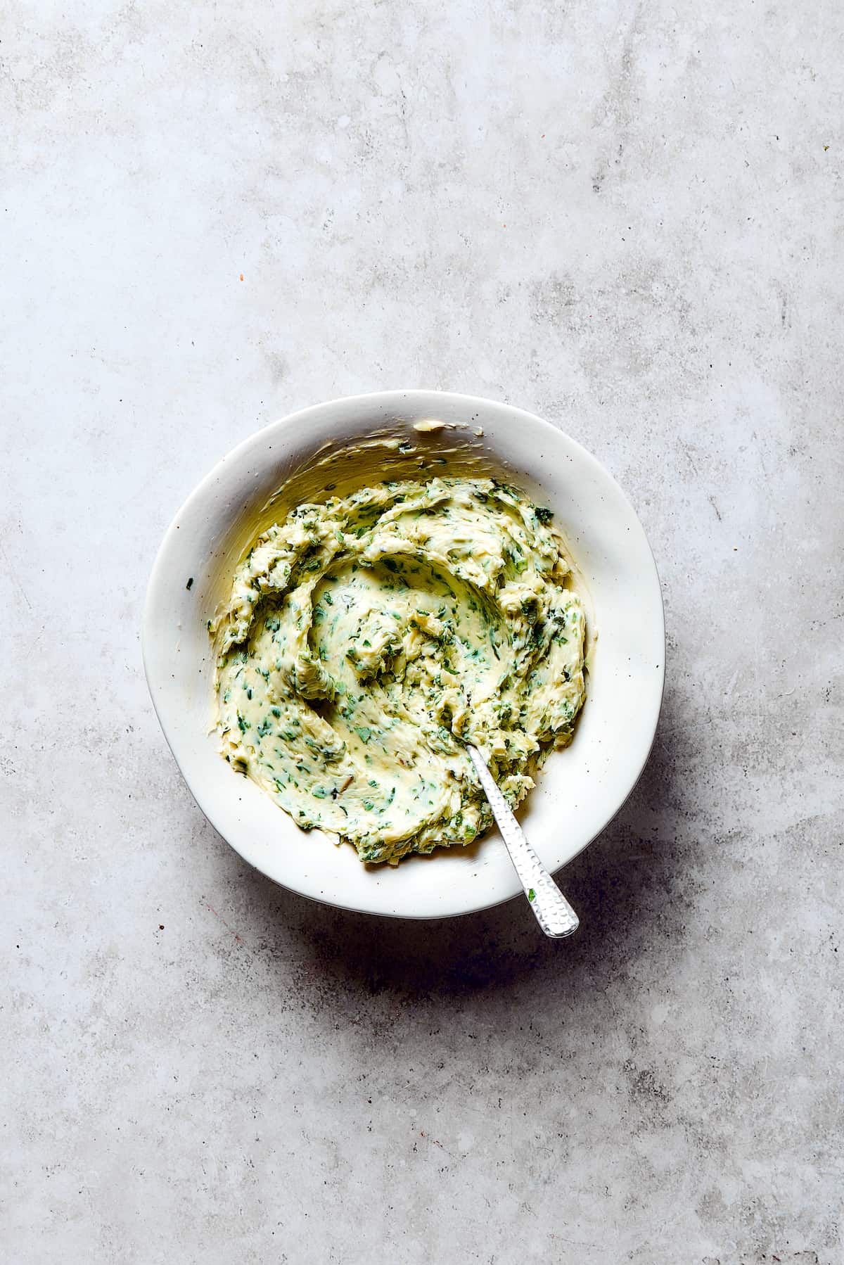 A dish of freshly mixed garlic herb butter, showing the green flecks of herbs.