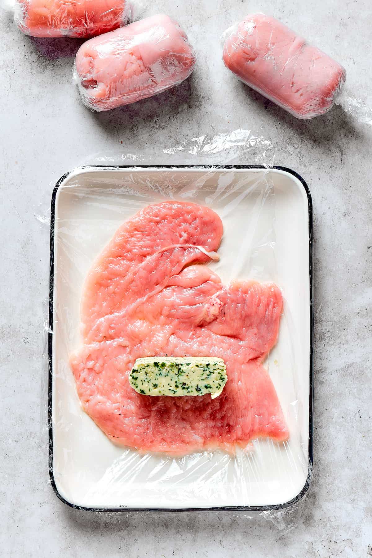 A slice of compound butter placed on a butterflied chicken breast, folded over.
