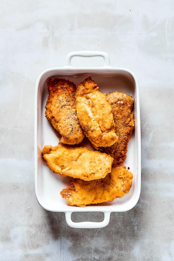 Breaded, browned chicken in a baking dish.