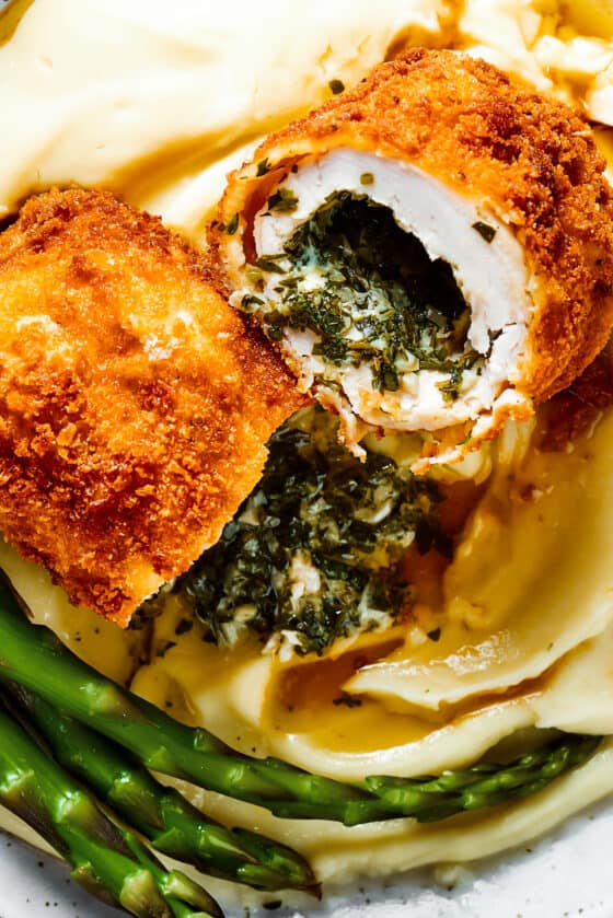 A serving of chicken Kiev cut in half to show the buttery filling.