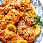 Homemade lemon chicken recipe arranged on a platter with parsley and lemon slices.