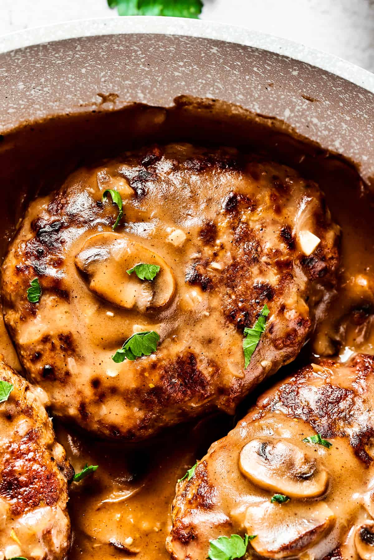Close up shot of a salisbury steak topped with mushrooms and gravy.