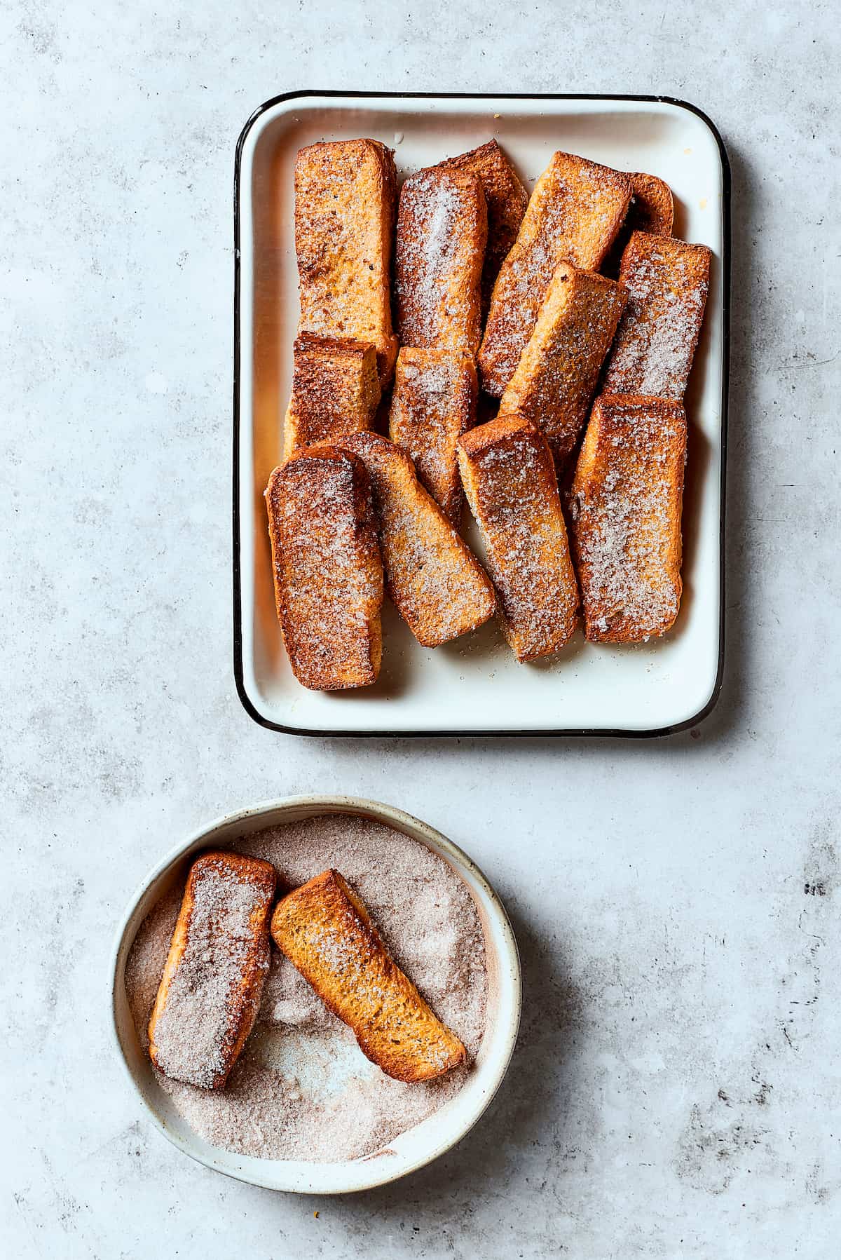 Rolling French toast sticks in cinnamon sugar.