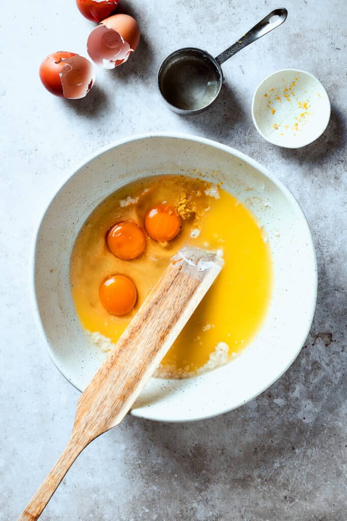 Stirring eggs into baking ingredients in a bowl.