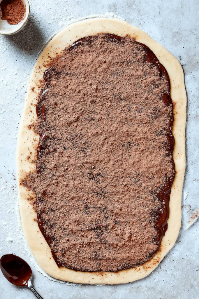 Chocolate spread out over a rectangle of dough and sprinkled with cocoa powder.