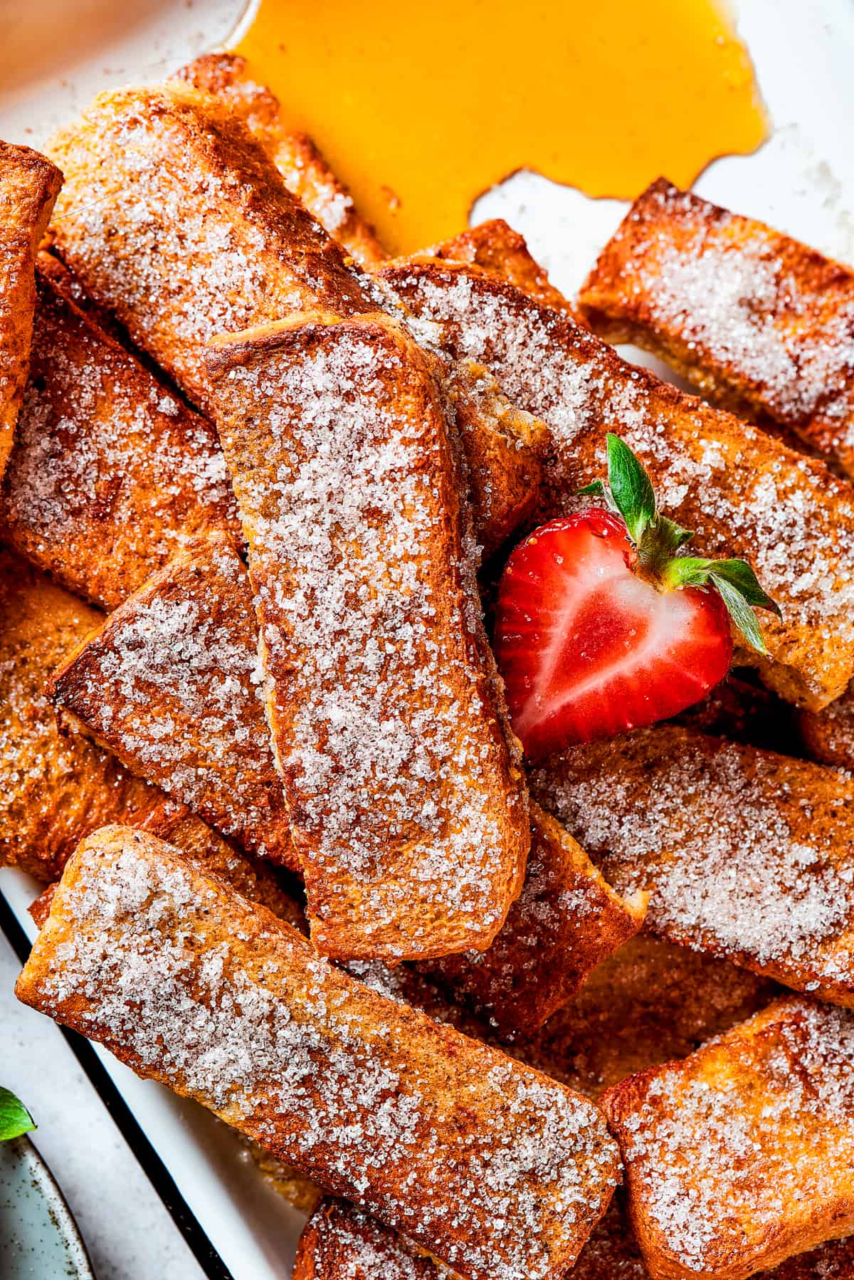 A shot of cinnamon-sugar-coated French toast sticks arranged on a white plate.