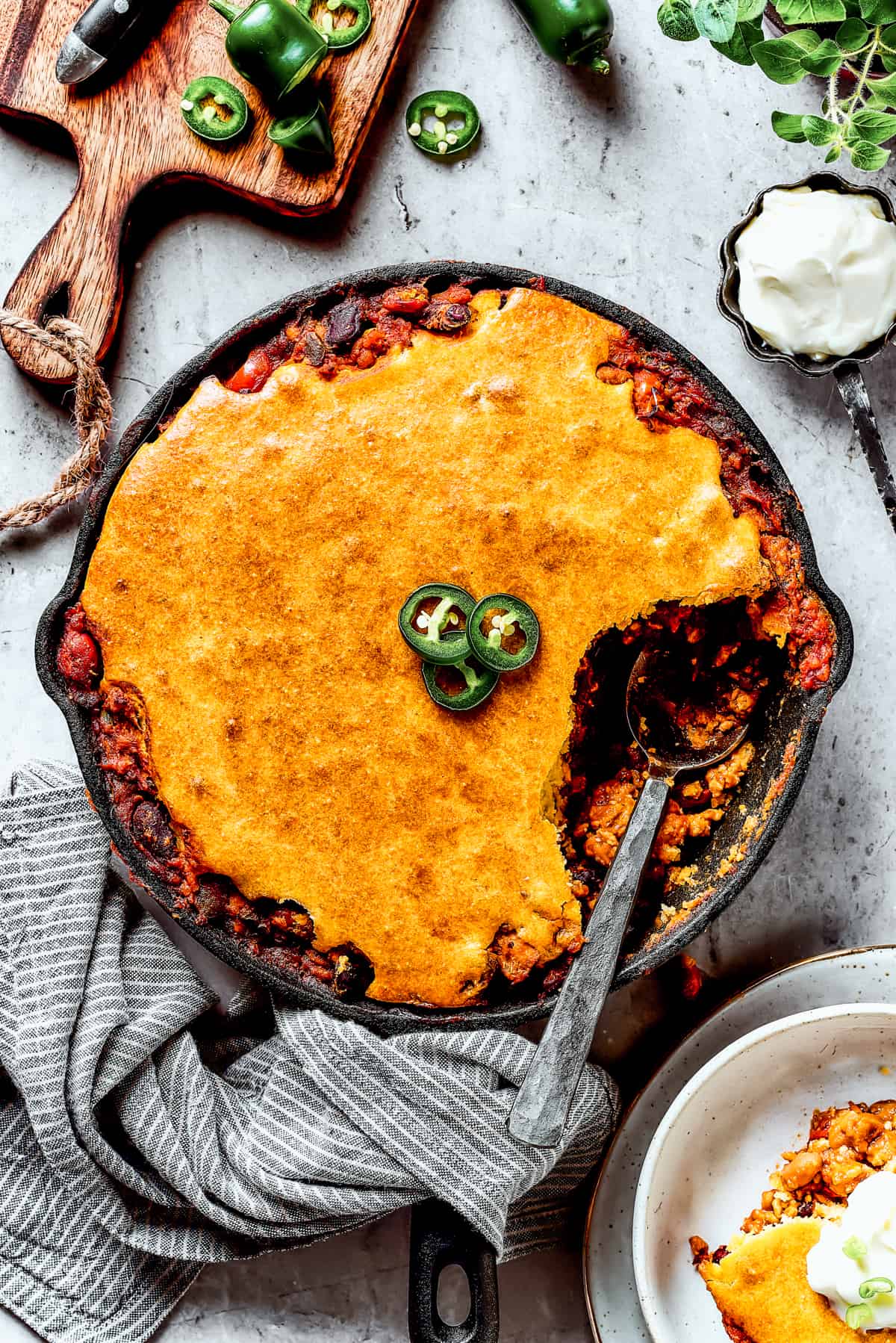 Chili cornbread casserole with a serving removed and a spoon resting in the skillet.