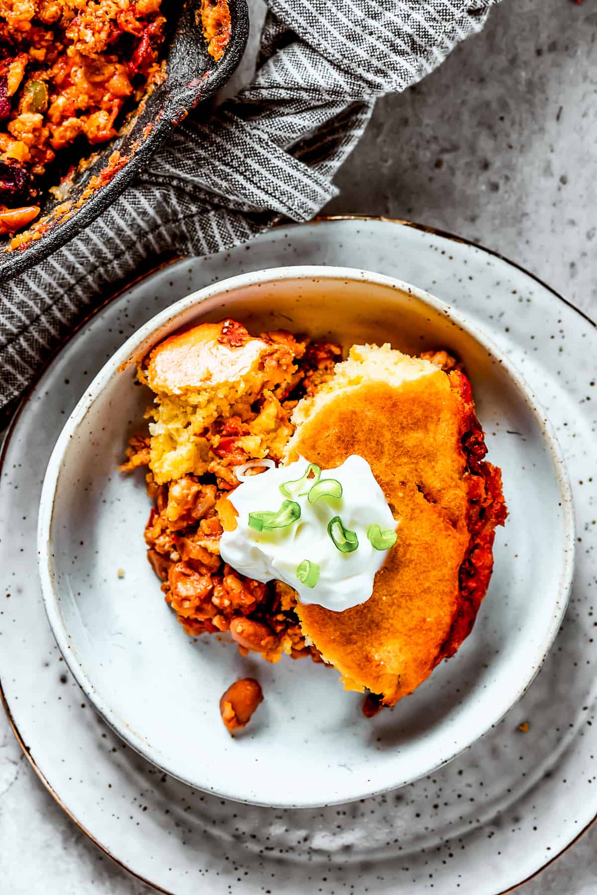 A serving of cornbread-topped turkey chili on an earthenware plate.