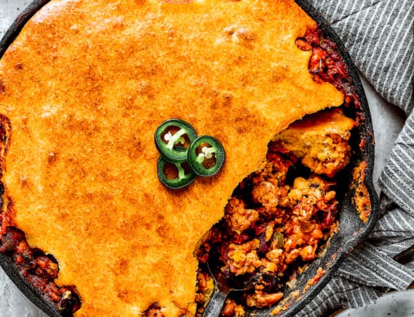 Overhead shot of a cast iron skillet with homemade Chili cornbread casserole and a serving removed with a spoon.