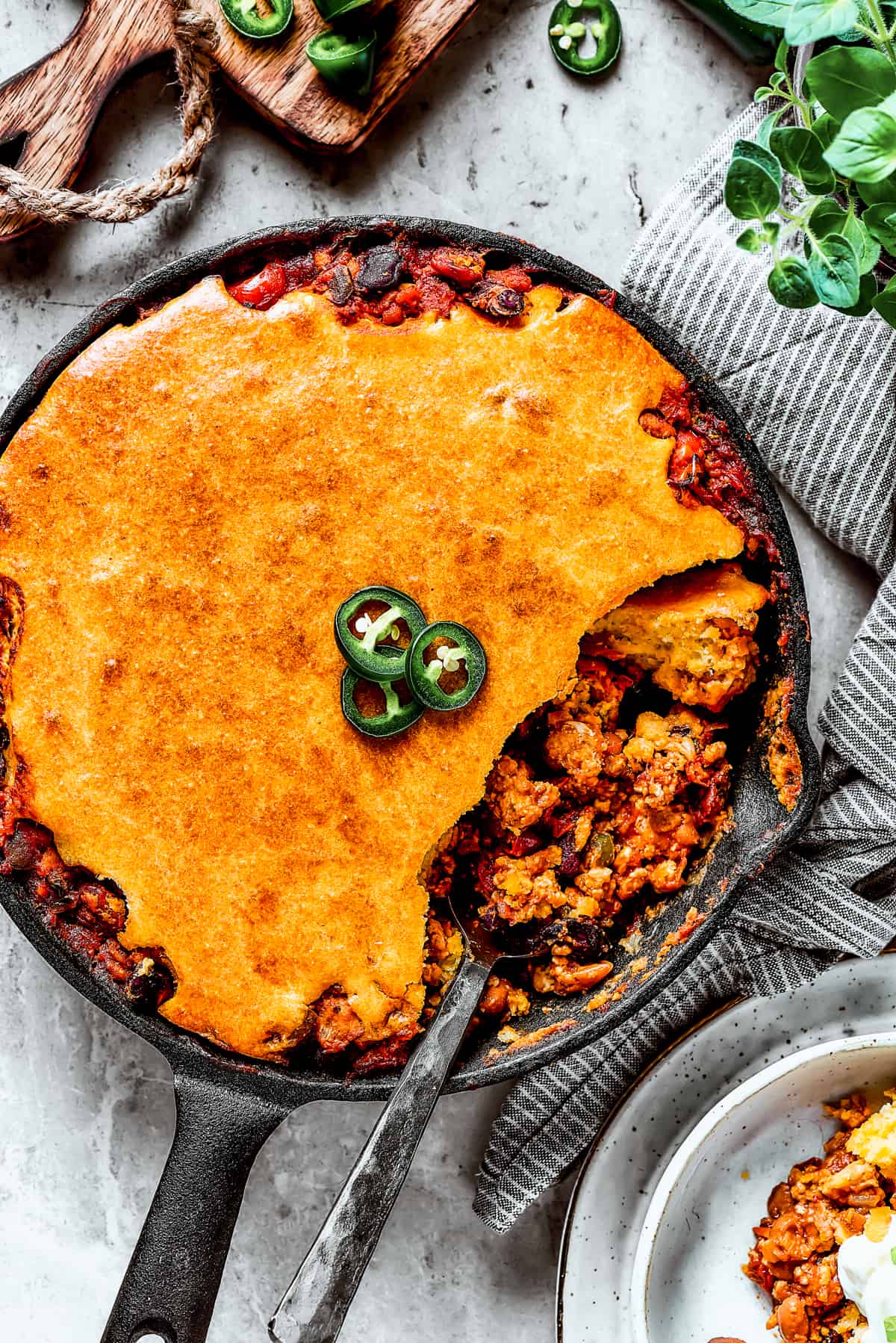 Overhead shot of a cast iron skillet with homemade Chili cornbread casserole and a serving removed with a spoon.