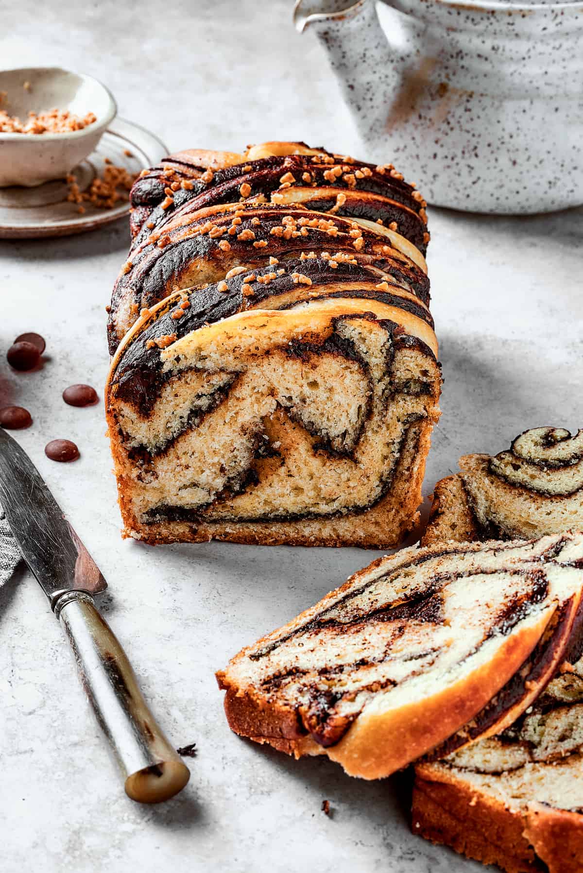 side shot of sliced chocolate babka with bread slices laid in front of it.