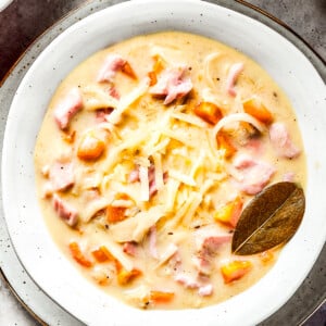 A bowl of creamy soup with a bay leaf in it.