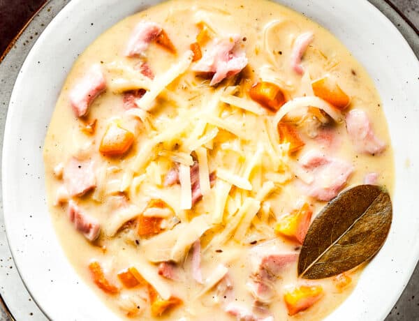 A bowl of creamy soup with a bay leaf in it.