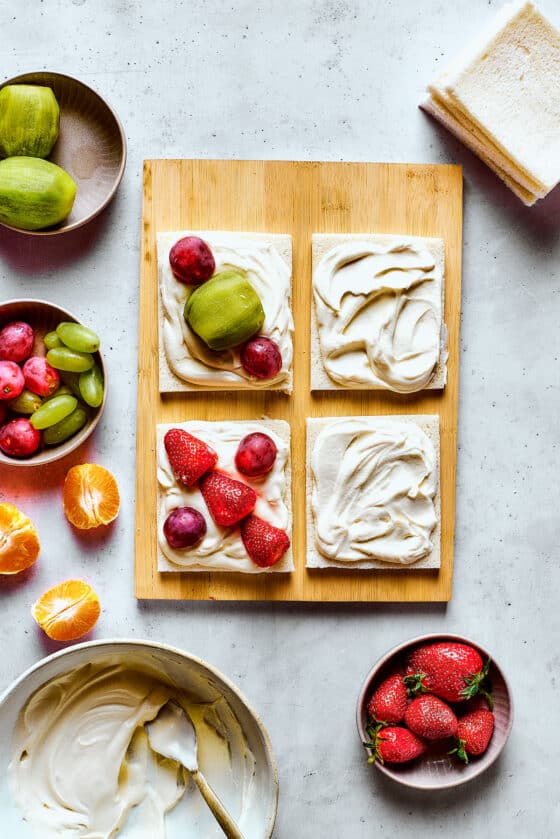 Arranging fruit on bread with whipped cream.