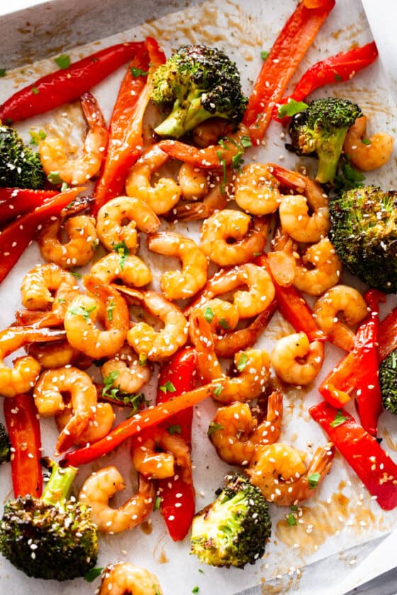 Overhead photo of a baking sheet with cooked shrimp, broccoli, and red bell peppers.