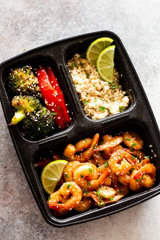 Photo of cooked shrimp, stir-fried veggies, and rice in a black container.
