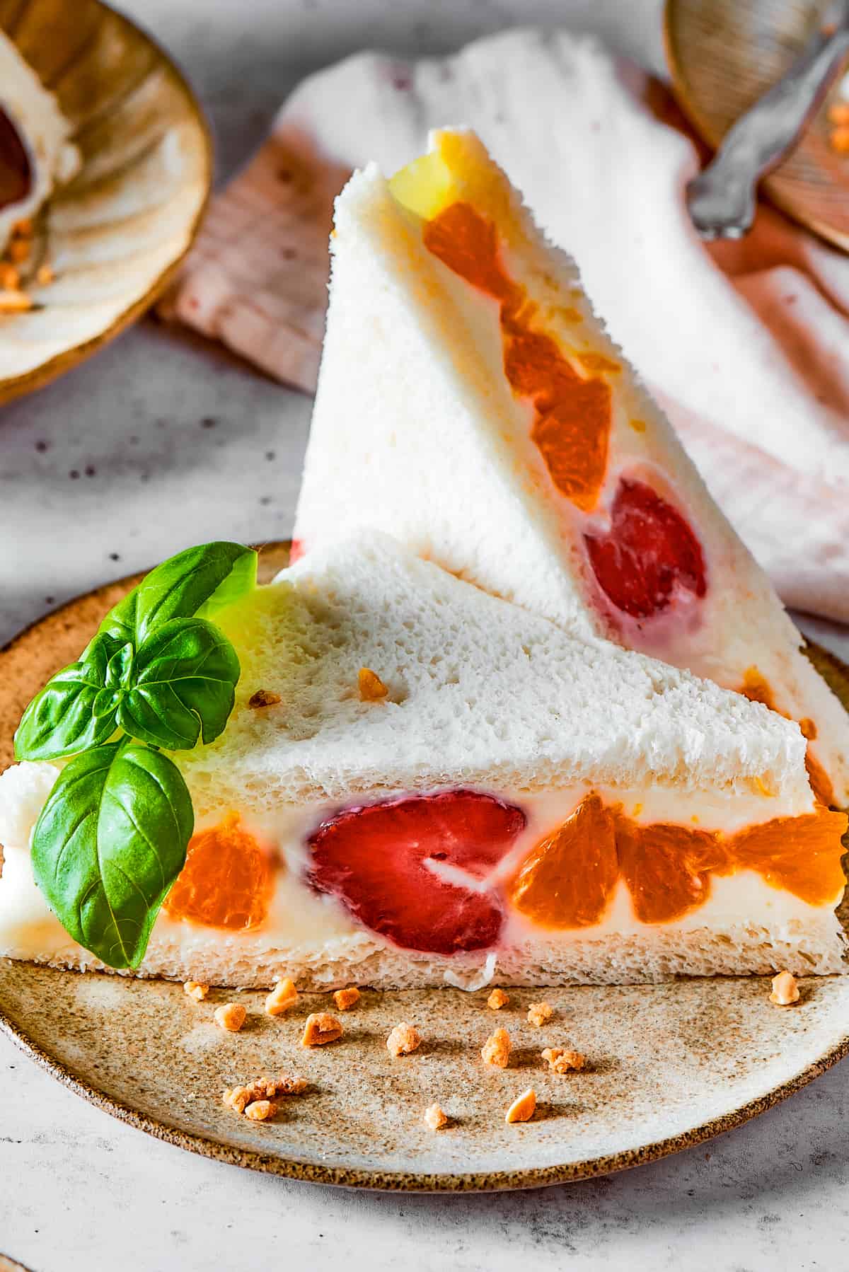 A sandwich made with white bread, mandarin oranges, and strawberries.