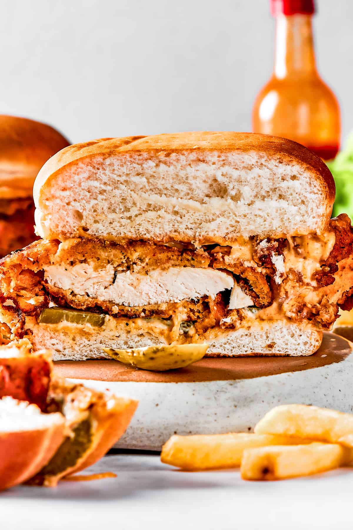 A homemade fried chicken sandwich cut in half to show the texture of the fried chicken and bun.