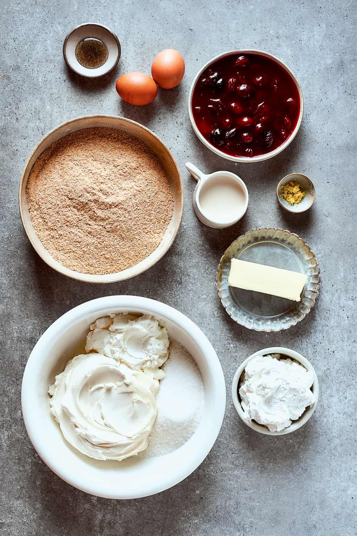 Ingredients for cherry cheesecake arranged on a work surface.