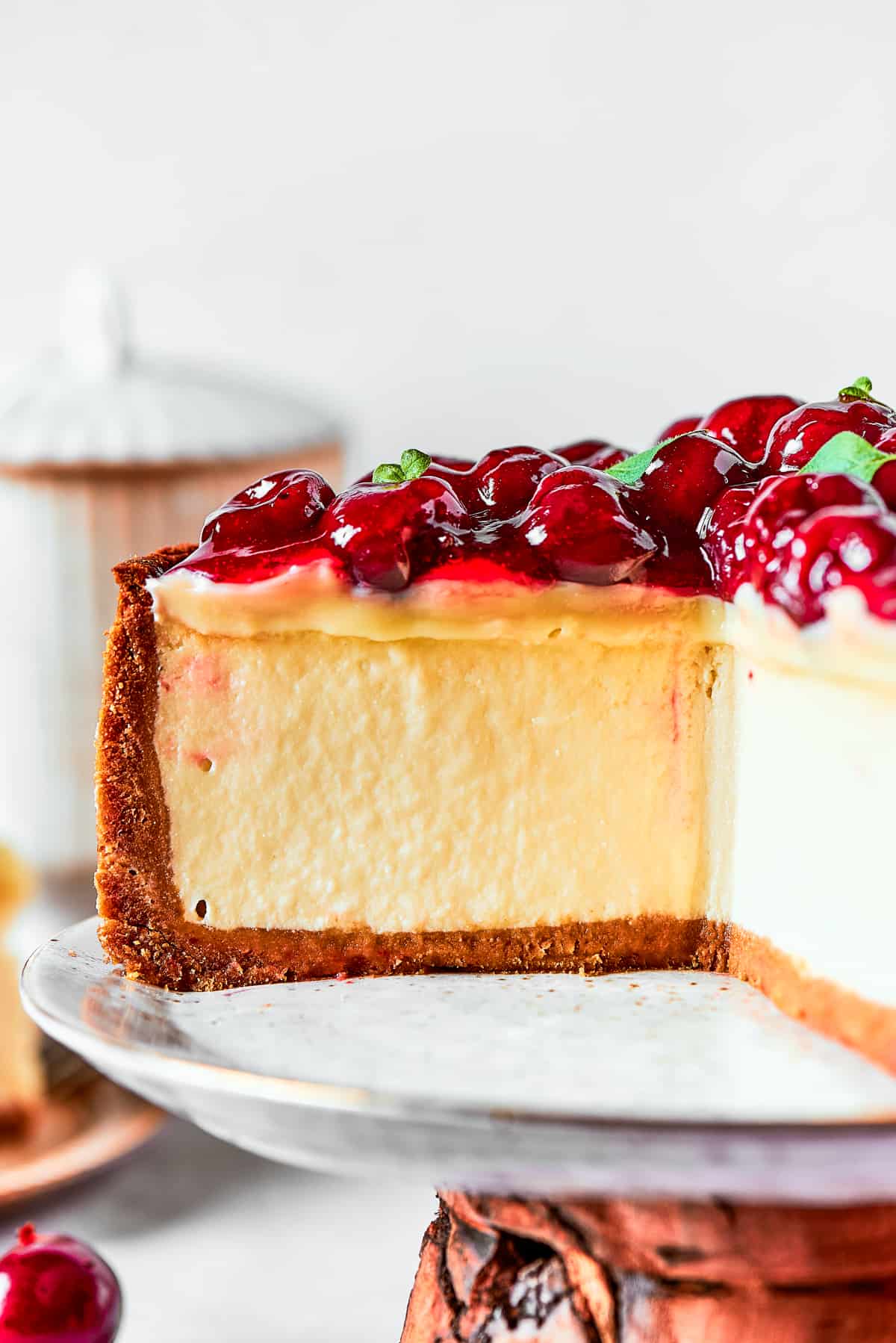 Close-up image of a cheesecake topped with cherries and placed on a cake stand.