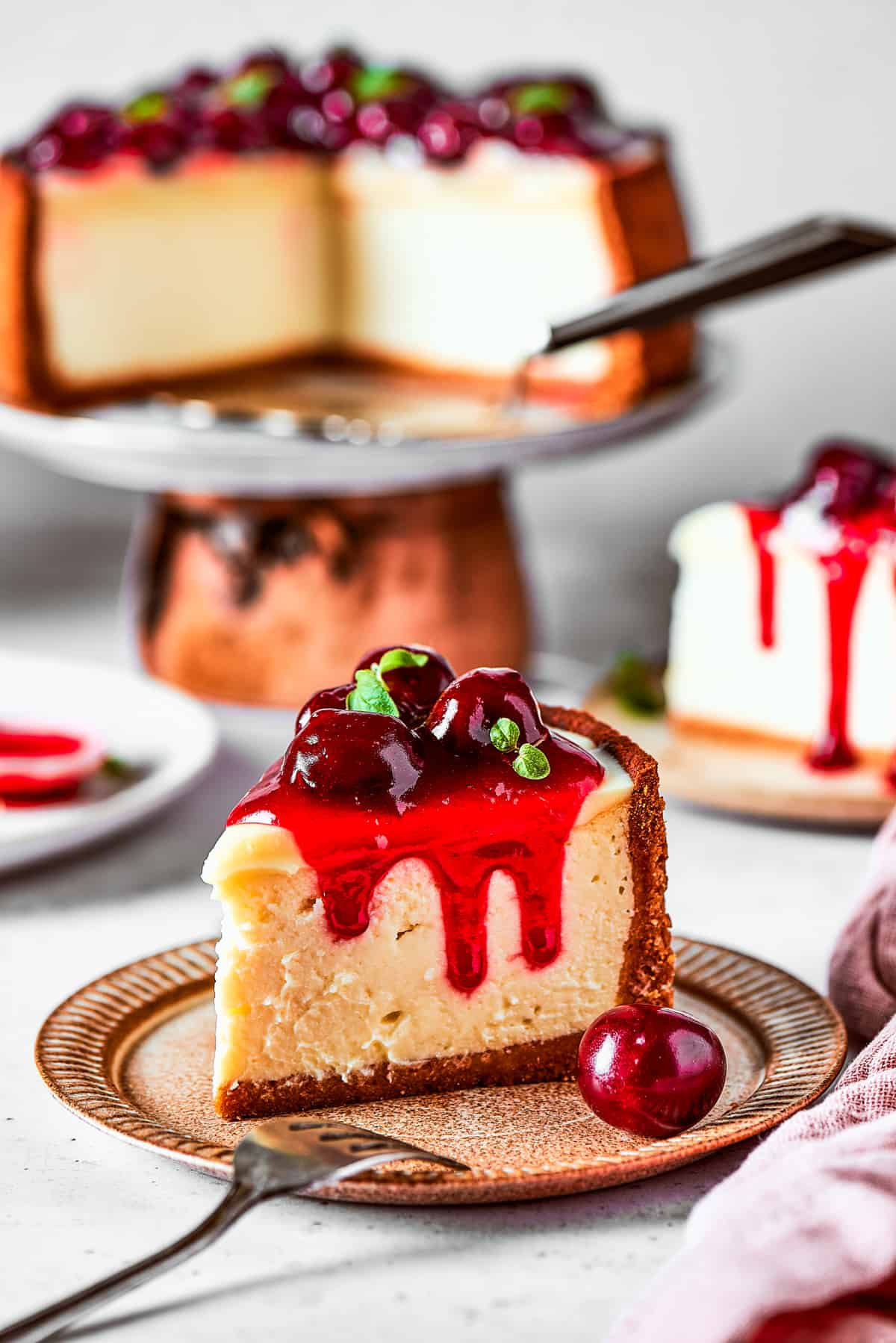 A slice of cheesecake topped with cherries and served on a dessert plate.