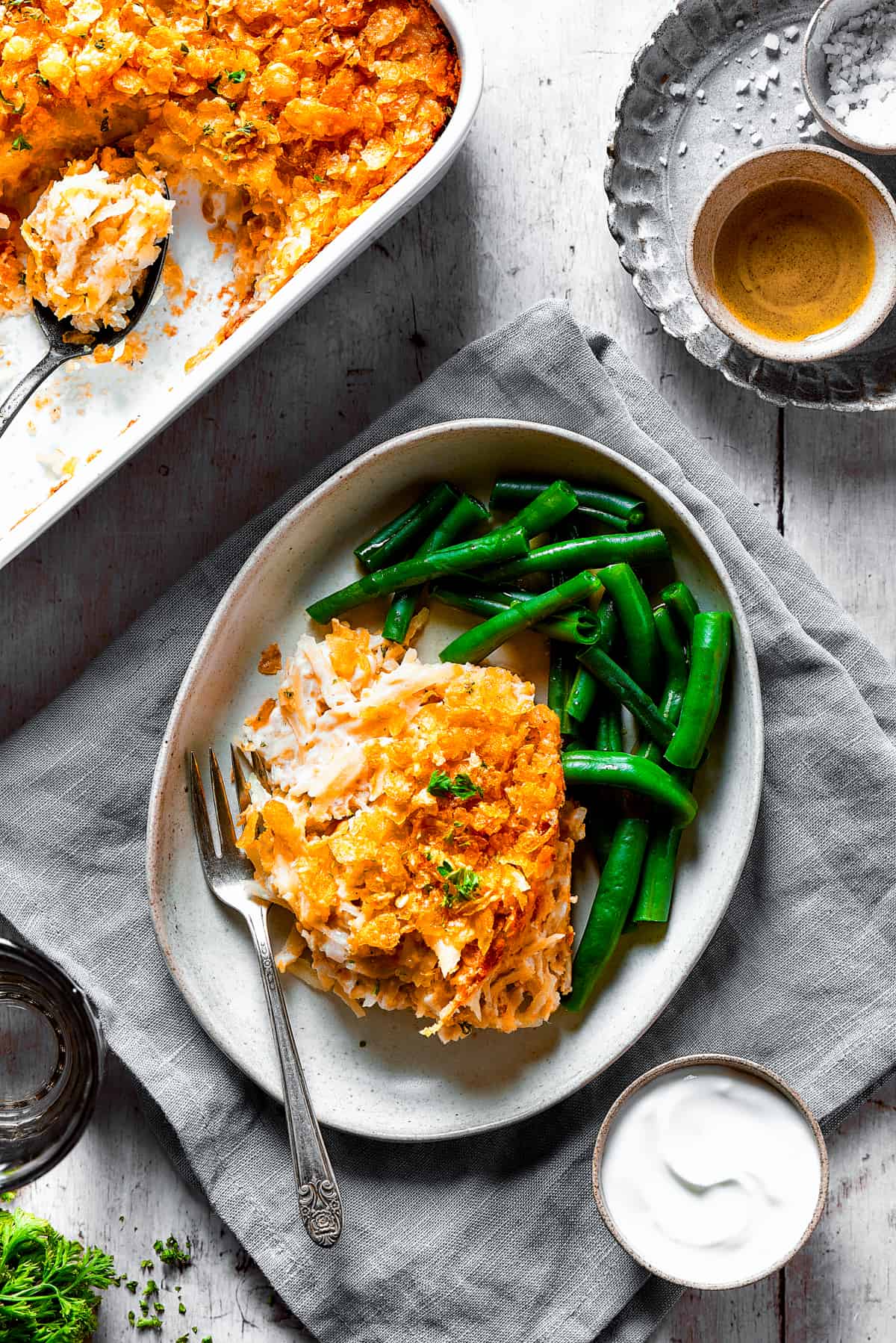 Overhead shot of hashbrown casserole on a dinner plate with green beans.