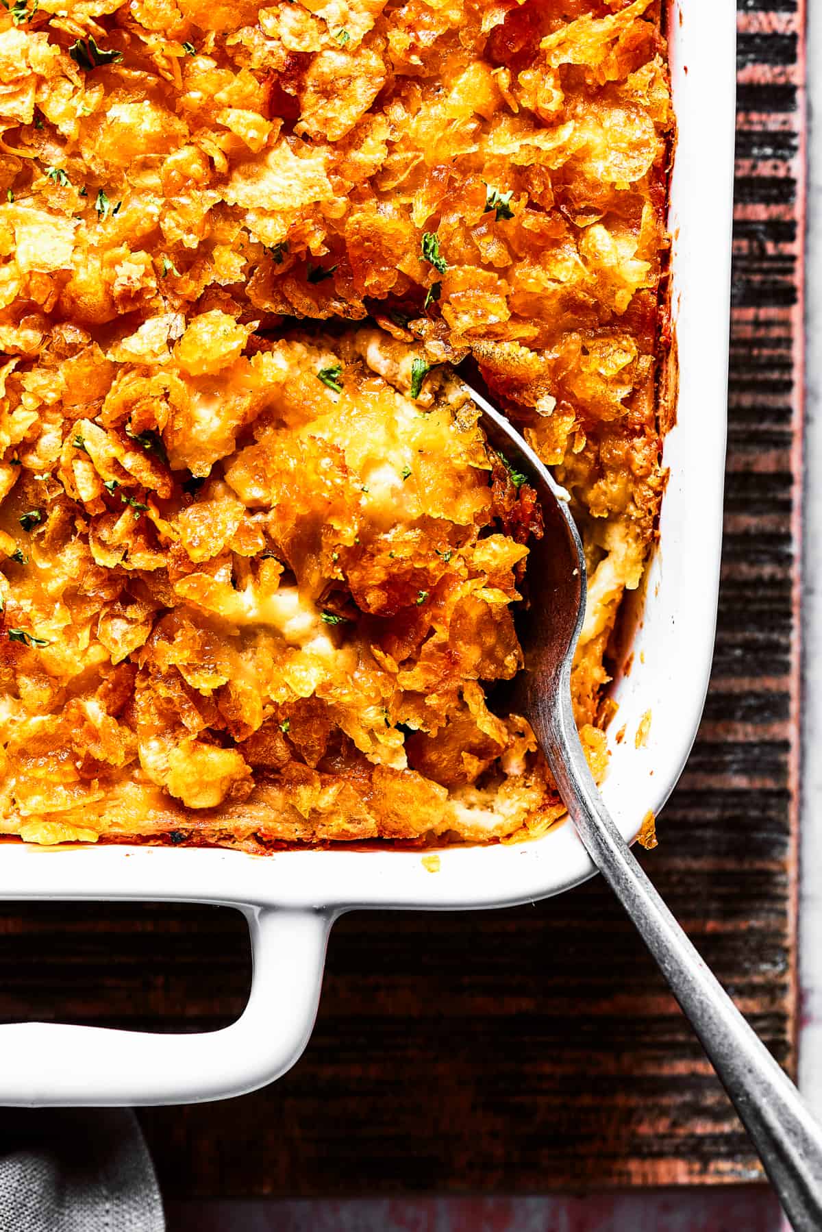 Close-up shot of a serving spoon in a casserole topped with cornflakes.