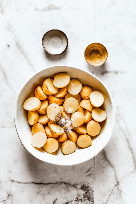 Cut potatoes in a bowl with salt, pepper, and oil.