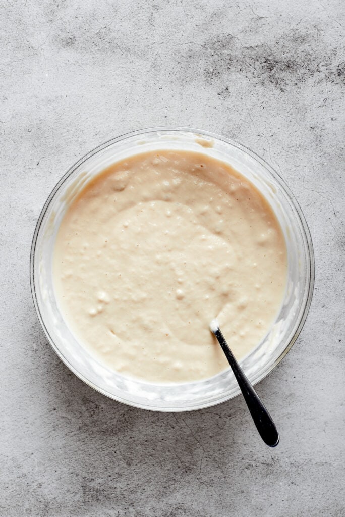 A mixing bowl with biscuit dough and a spoon