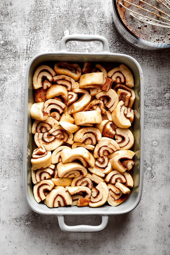 Overhead view of pieces of unbaked cinnamon rolls in a baking dish
