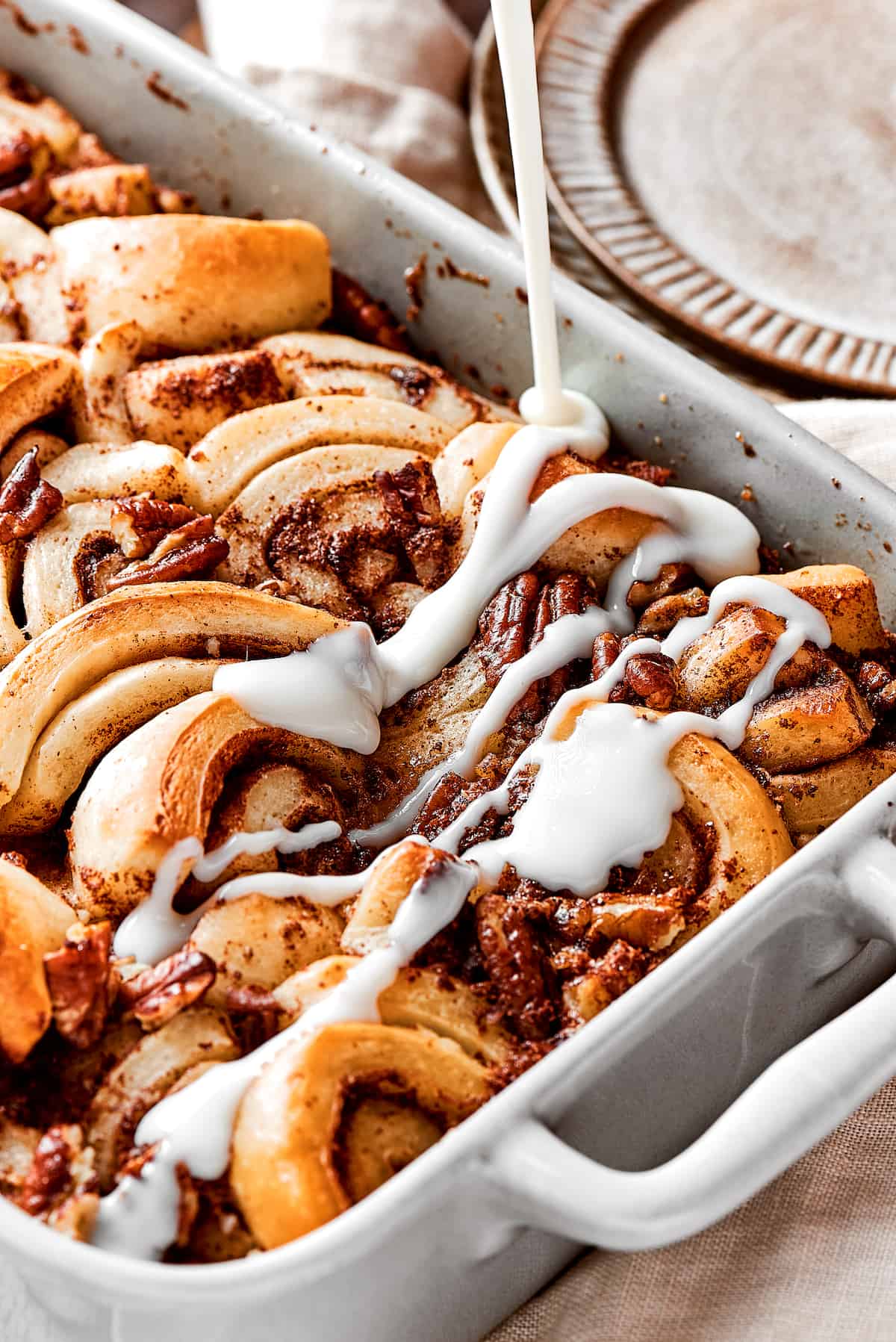 A cinnamon roll casserole with icing being drizzled over the top