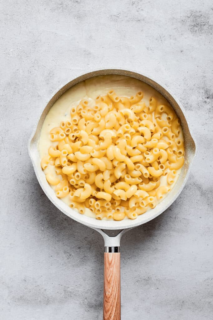 A sauce pan with macaroni sitting on top of a cheese sauce.