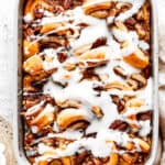 Overhead view of a cinnamon roll casserole in a baking dish, covered in icing