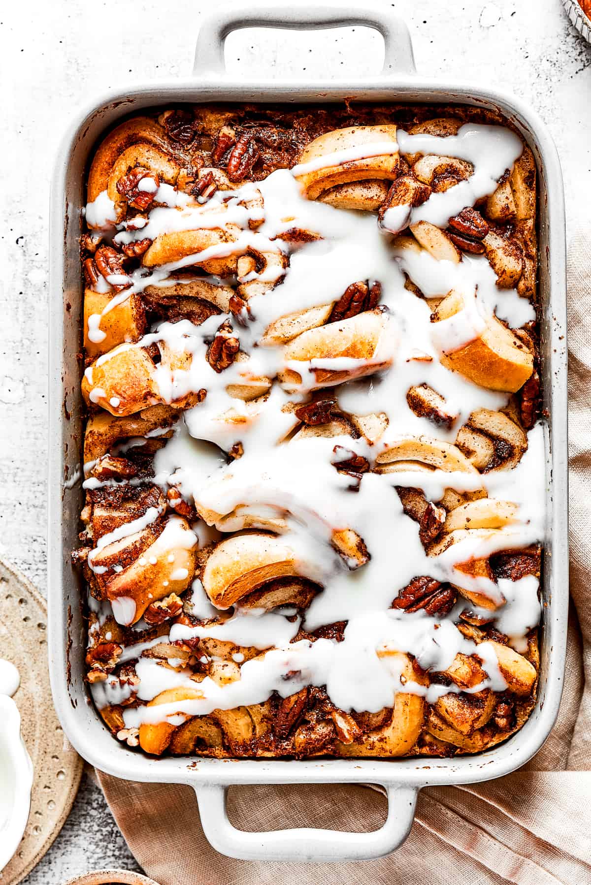 Overhead view of a cinnamon roll casserole in a baking dish, covered in icing