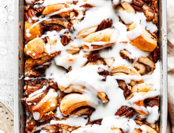 Overhead view of a cinnamon roll casserole in a baking dish, covered in icing