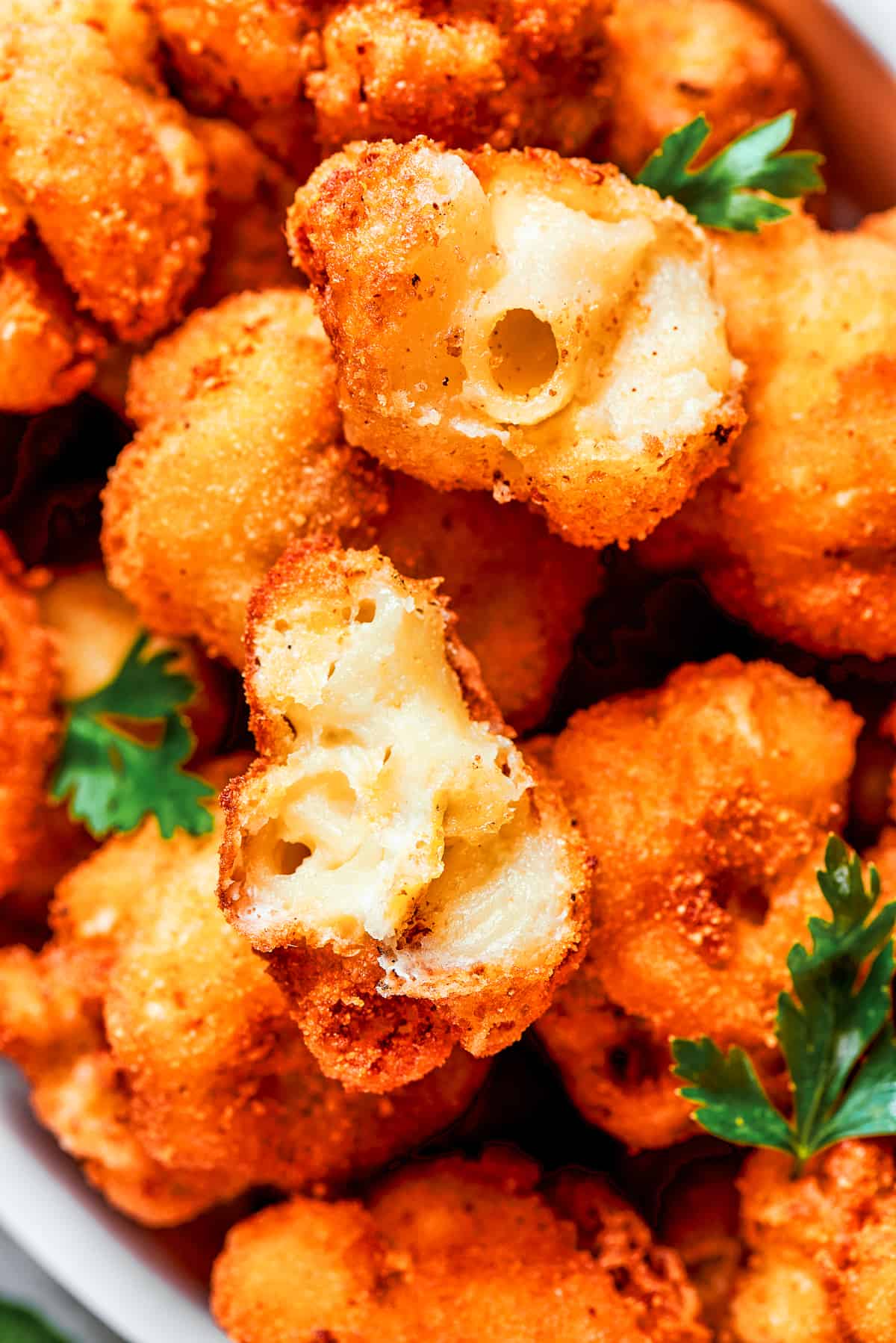 Close-up image of fried mac and cheese bites cut in half to showcase its texture inside.