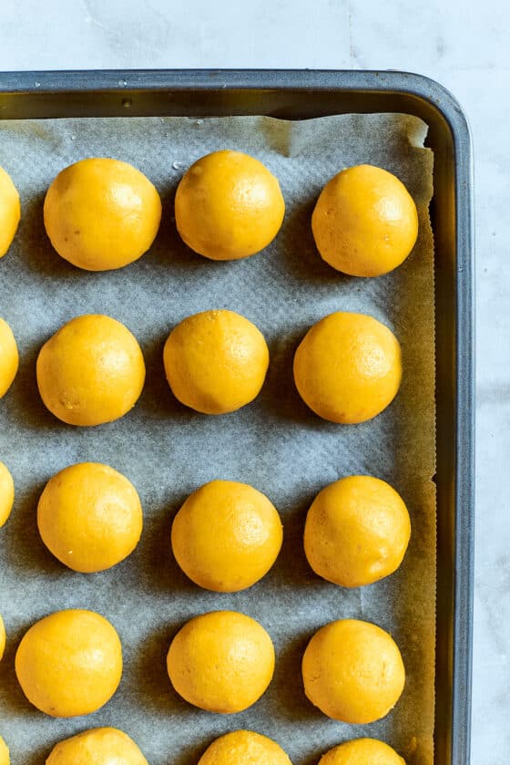Overhead view of lemon cookie dough balls on a baking sheet.