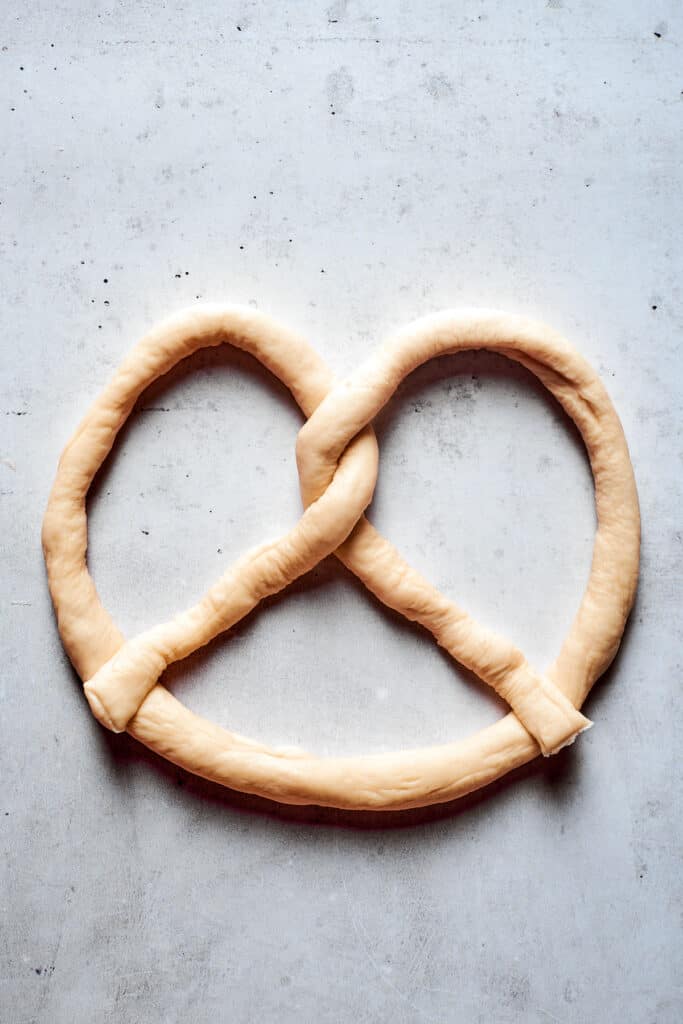 A rope of soft pretzel dough is formed into a pretzel.