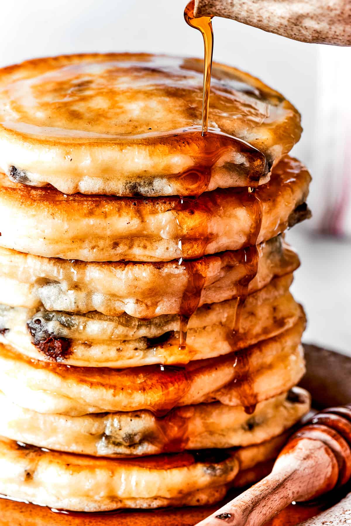 Pouring maple syrup over a stack of fluffy pancakes.