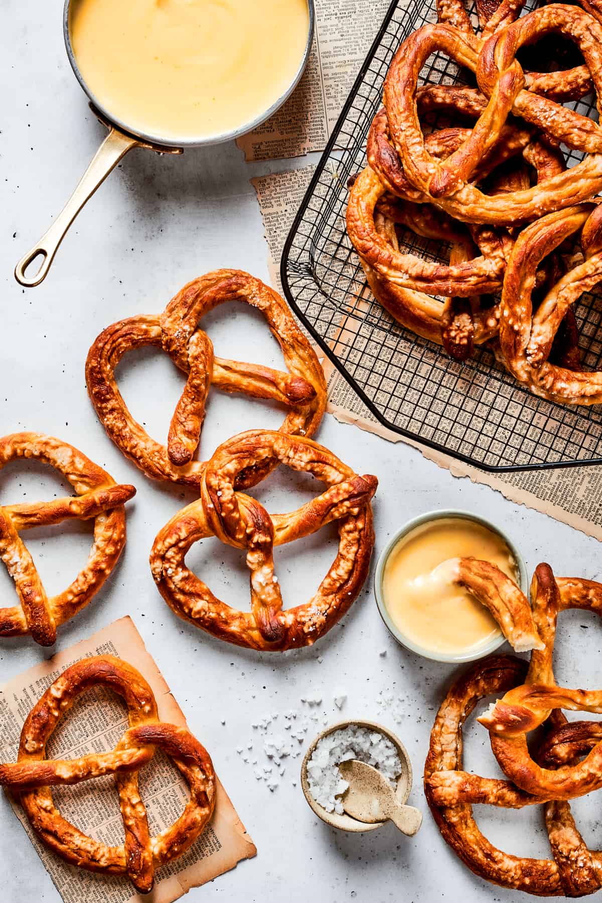 Baked soft pretzels are shown on a rack with cheese sauce alongside.